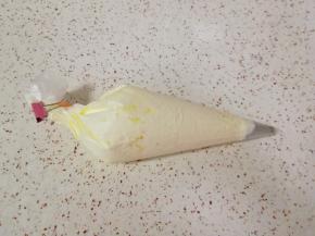 裱花袋底部剪一个口，装入圆孔裱花嘴，将奶油装入裱花袋，用夹子夹上。 