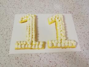 取两个“1”字形蛋糕片摆好，挤上奶油。 