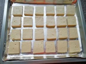 烤盘里铺上锡纸，将准备好的豆腐块摆在烤盘里。 