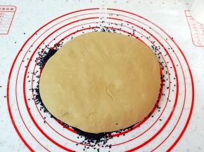 面团压扁沾满黑芝麻，慢慢的把黑芝麻和面团揉在一起。 