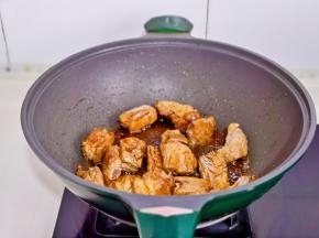 起油锅加入冰糖炒化至褐色，加入排骨翻炒。