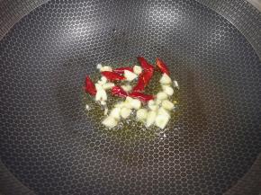 炒锅内倒适量的菜籽油烧热，下入大蒜和干红辣椒炒香。 