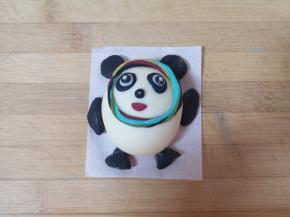 剩下的黑色的面团分成6等分，分别做出冰墩墩的四肢，沾水粘在相应的位置。