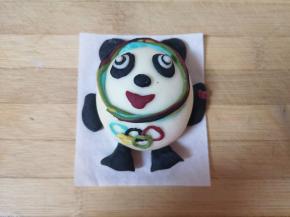 最后用彩色的面团做出奥运五环，沾水粘在冰墩墩肚子的位置，用红色的面团做一个小爱心，沾水粘在冰墩墩手心，一个可爱的冰墩墩就做好啦！