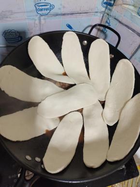 把擀好的面片贴在锅边！（放面片之前记得要把鸭肉翻炒均匀，水要没过鸭肉一点儿为宜！）