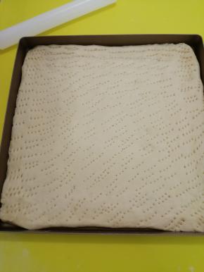 把发酵好的面团移到揉面垫上揉一下排气，然后用擀面杖擀薄，把擀好的面皮放在烤盘里，用叉子多叉些小洞，放在温暖处进行2次发酵