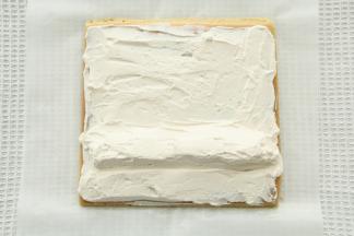 毛巾面在下，修出斜边，抹上一层焦糖奶油，尾部薄一些，1/3处堆高。