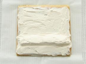 毛巾面在下，修出斜边，抹上一层焦糖奶油，尾部薄一些，1/3处堆高。