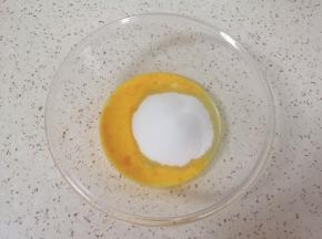 玻璃碗中打入一个鸡蛋，加入细砂糖。