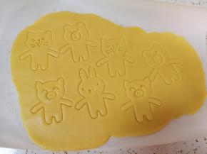 台面上铺一张油纸，取一块冷藏过的面团放在油纸上，再盖上一层油纸擀开，用动物饼干模具压出小动物造型。 