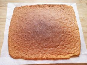 蛋糕烤好以后从烤箱里取出，撕开周围的油纸晾至温热。 