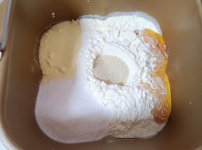 加入高筋面粉、奶粉、细砂糖和蜂蜜，面粉中间挖个小坑放入发酵粉盖起来。