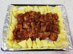 烤盘里铺上锡纸，刷上一层食用油，土豆切成滚刀块，和腌好的排骨一起放入烤盘。