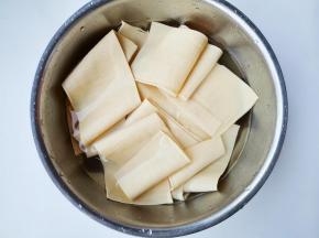 豆皮切成宽长条，温水泡开洗净。