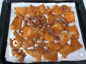 烤盘里铺上锡纸，刷上一层花生油，放上腌好的鱿鱼。 