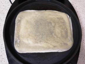 电饼铛刷上一层食用油预热，放入鸡蛋灌饼生胚，饼的上面和边缘也刷上一层食用油。
