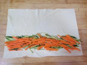 豆皮铺在案板上，放上切好的黄瓜胡萝卜丝卷起来。 