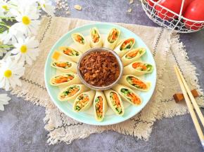 盛有鸡蛋酱的蘸碟放在盘子中间，豆皮蔬菜卷围着蘸碟摆一圈。 