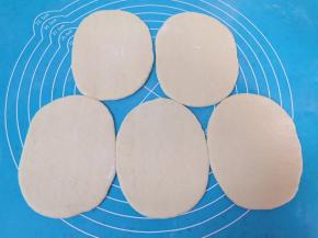 将小剂子压扁，擀成椭圆形的盒子皮。 