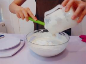 将打好的动物性淡奶油，分2次倒入奶酪糊里。用橡皮刮刀翻拌均匀，成为芝士慕斯馅