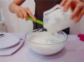 将打好的动物性淡奶油，分2次倒入奶酪糊里。用橡皮刮刀翻拌均匀，成为芝士慕斯馅
