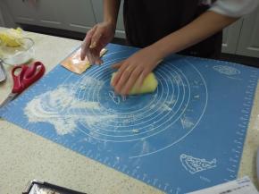 撒些低粉在面板上，预热烤箱170度，手沾下低粉，将面团沾粉反复对折，搓成长圆条。