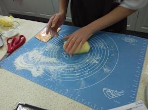 撒些低粉在面板上，预热烤箱170度，手沾下低粉，将面团沾粉反复对折，搓成长圆条。