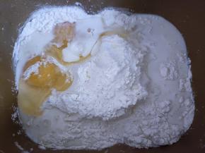 面包机内放入面粉、牛奶、鸡蛋，盐和糖对角放，中间挖个洞放入酵母。启动面包机揉面程序20分钟，加入黄油，继续揉20分钟。