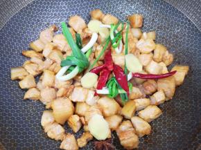 下入小葱、生姜片、八角和干红辣椒炒出香味。 