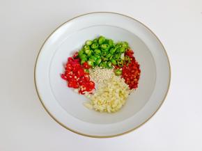 把线椒，小米椒，蒜，切好放在碗里，加上辣椒粉，芝麻。