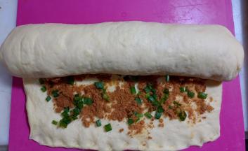 底边压薄，从上往下卷起。卷好后两头捏紧。盖保鲜膜松弛15分钟。