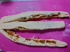 将松弛好的面团轻轻压扁一些，用刀将面团切成三条。