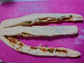 将松弛好的面团轻轻压扁一些，用刀将面团切成三条。