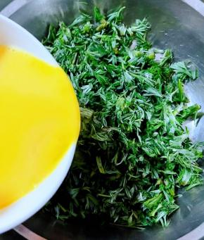 搅拌好的蛋液倒入切碎白蒿中