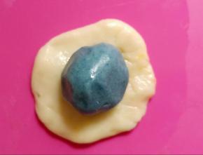 取一个水油皮面团按扁，包入一个油酥材料。