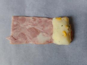 培根切两段，取一团土豆捏成圆柱形，放在培根上。