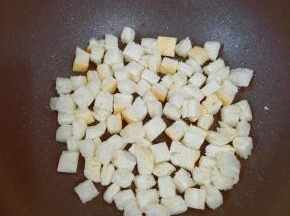 然后把面包块放入锅中，煎到面包块微黄