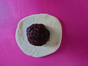 松弛好将面团檊开，包入一个紫米馅团。