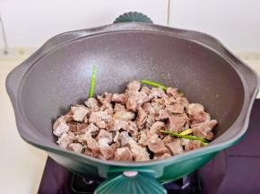 起油锅，加入葱姜煸炒再倒入牛肉翻炒。