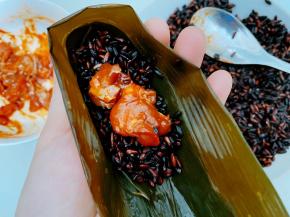 取两张粽叶折成漏斗状，装入黑米和鸡肉
