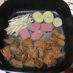 电热锅插上电源，放入一张烤肉纸，刷一层油！把腌制好的五花肉片放进去烤！把喜欢吃的配菜一起放在一边烤！