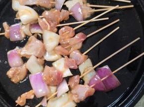 电饼铛预热，刷一层油，把串好的鸡肉串放进去烤！再在鸡肉表面也刷一层油！