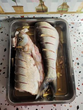 鱼太大了，我把它从鱼身中间切开成两段了！在鱼身上划几刀，放入料酒，生姜，适量盐抓拌均匀腌制半个小时！