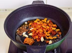 起油锅加入花椒，蒜，辣椒碎，火锅底料炒出香味。