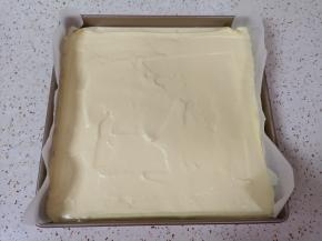 烤盘里铺上油纸，倒入蛋糕糊，轻震几下震出大气泡，用刮刀刮平表面。