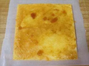反过来倒扣在一张大一点的油纸上，切去四边，抹上杏子果酱（果酱里面还有大块的果肉哦），卷起来放入冰箱定型2小时。 