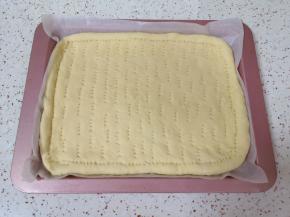 发酵好的面团揉光排气，擀成和烤盘大小差不多的饼底，放入烤盘，用叉子扎上小孔。