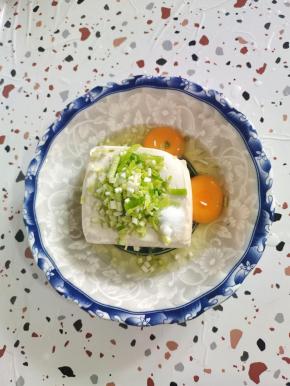 嫩豆腐放入碗中，磕入两个鸡蛋。放入适量的葱花和盐！