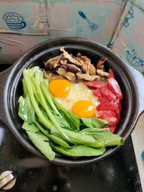 米饭熟了以后，放上腊肠、香菇、青菜，中间 打入两个鸡蛋！