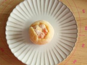 擀开或者用手压薄，放上一整颗橘子。